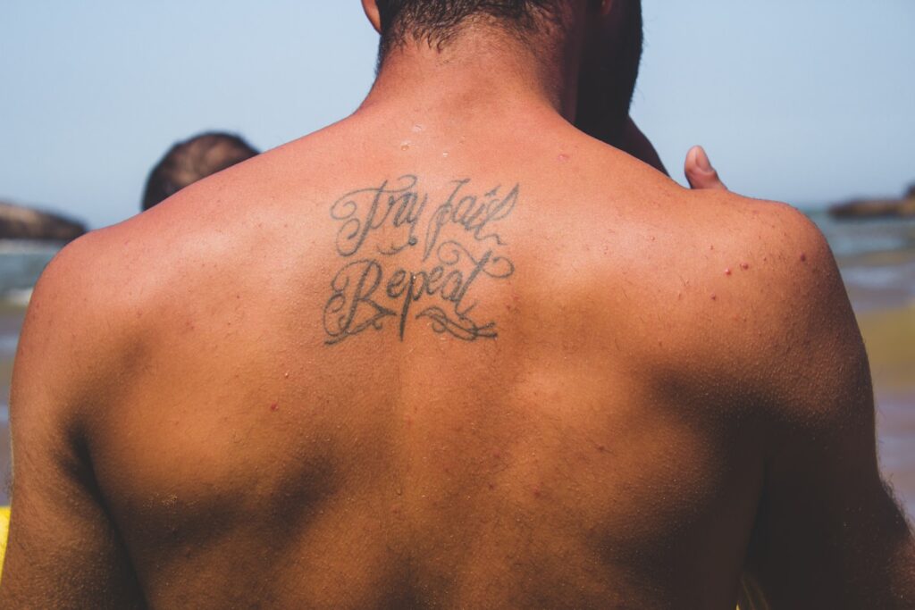 person with try fail repeat tattoo at back