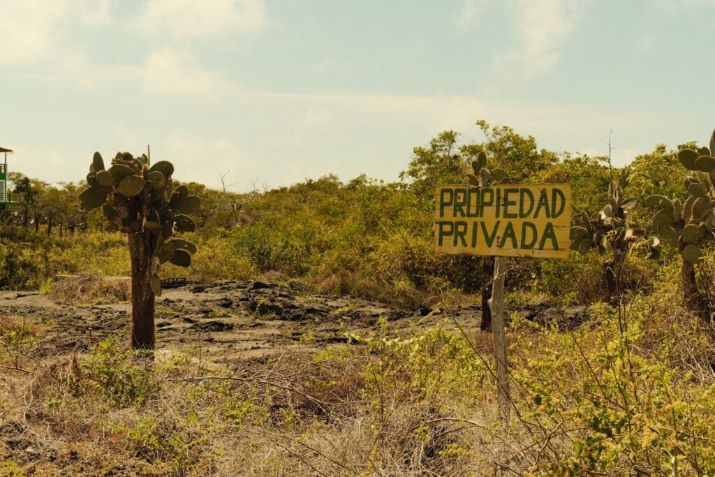 Private property sign in a dry, brushy landscape.